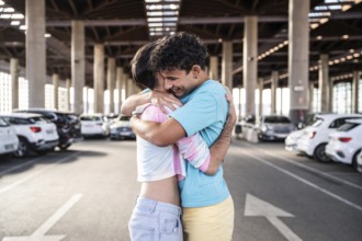 A joyful gay couple shares an embrace in a spacious urban parking garage, surrounded by parked cars