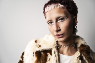 A portrait featuring a woman looking at camera with bold white eye makeup and piercings, wearing a