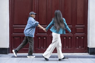 A joyful Latin lesbian couple holding hands as they walk together. They are both wearing casual