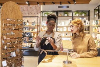 A retail employee helps a customer choose eyeglasses in a stylish boutique. The modern store is