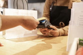 A customer makes a purchase using a point-of-sale terminal in a cosmetics store. A paper shopping