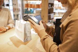 A retail worker processes a transaction at a cosmetics store. The scene captures the sale