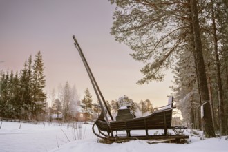 A vintage wooden sleigh rests in a serene snowy forest in Swedish Lapland at sunset. The peaceful