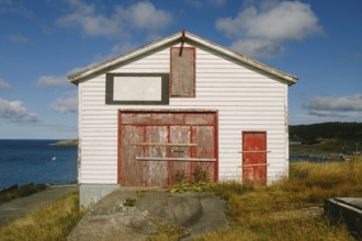 A weathered white and red storage building in Flatrock, Newfoundland & Labrador, Canada. The
