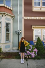 A young woman with red hair stands beside classic architecture in St. John's, Newfoundland &
