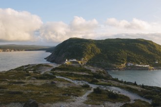 A serene sunset casts warm light over the rugged landscape of Signal Hill, St. John's, showcasing a