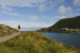 Back view of unrecognizable woman enjoying a serene walk along a coastal trail in Signal Hill, St