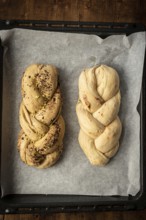 Top view of freshly baked Bakbah breads on parchment paper, featuring one loaf topped with