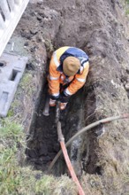 Technician connects fiber optic cable in the ground, Schleswig-Holstein, Germany