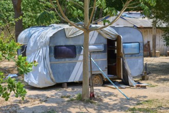 An outdated blue caravan stands in shade under trees in a rural setting, Pantanal, Mato Grosso,