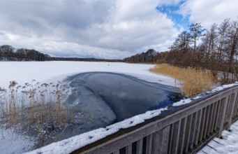 View of the church lake covered with ice and snow on the bridge tour, a hiking trail with a wooden