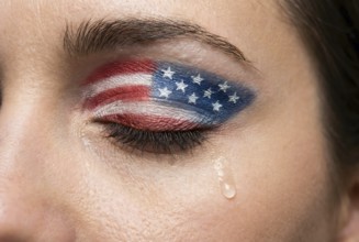 Close up of sad woman's eye with USA flag eyeshadow and tears representing political and social