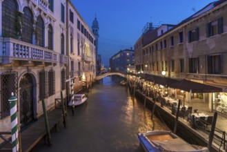 Dinner with restaurant on the canal, in the back the tower of the church of Santa Maria della