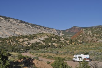 An RV parks in a picturesque mountain landscape with clear skies, Dinosaur National Monument, Utah,