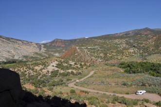 View of a valley with an RV on a road surrounded by mountains, Dinosaur National Monument, Utah,