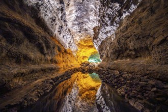 Lava tunnel, illuminated lava cave with perfect reflection in an underground lake, Cueva de los