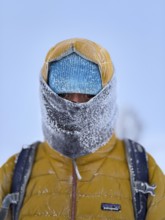Young man wearing thick winter clothes, down jacket and scarf, with frozen snow in cold weather,