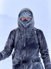 Young woman wearing thick winter clothes, down jacket and scarf, with frozen snow in cold weather,