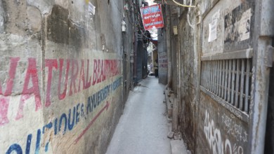 Narrow urban alley with colorful advertising banners and graffiti on the walls, Delhi, India
