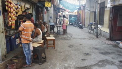 People look at a small kiosk on a road bike, busy street scene with people and shops, in an urban