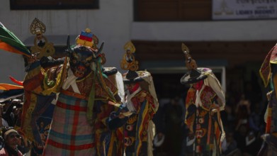 Colourful masked dancers perform a traditional performance in front of an audience, traditional