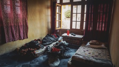 A simple room in a mountain village in the Indian Himalayas with two beds, backpack and cinder and
