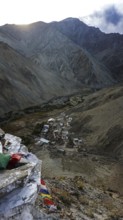 A small village surrounded by mountains in a remote valley under cloudy skies, trekking in Ladakh,
