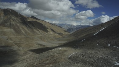 Wide, barren valley with mountains and clouds on the horizon, trekking in Ladakh, Stok la,