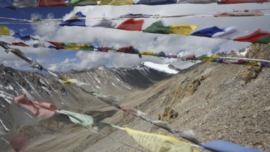Colourful prayer flags flutter against a high-mountain backdrop, trekking in Ladakh, Stok la,