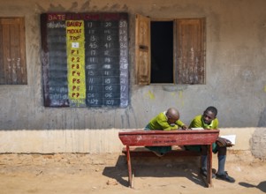 Schoolchildren in school uniform with notebooks sitting at a school desk in front of the classroom,