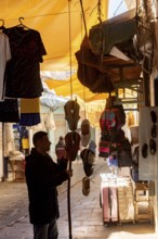 Tunis, Tunisia 4th May, 2024 A Tunisian man hanging traditional slippers outside of a shop in the