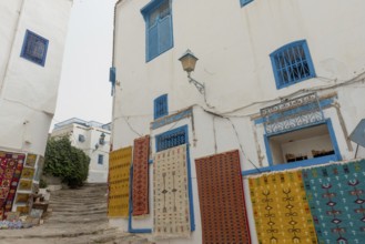 May 17th 2024. Sidi Bou Said, Tunisia. Tourist souvenir rugs hanging outside a store in the narrow