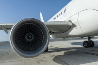 Unidentified plane engine and fuselage parked on airport runway with blue sky and copy space