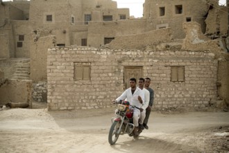 Siwa, Egypt. April 15th 2018. Three Egyptian men riding a motorcycle in the ruins of Shali