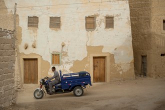 Siwa, Egypt, April 11th 2018 Motorcycle pick-up being driven through the mud brick houses of Siwa