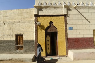 Aswan Egypt. January 10th 2013 Nubian Muslim man leaving a brightly coloured Mosque on Elephantine