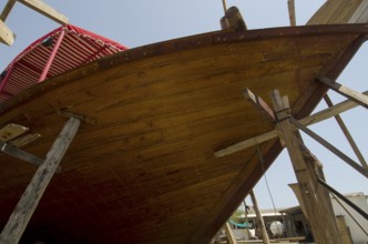 Sur, Oman. May 27th 2014 The wooden hull of a traditional Omani Dhow under construction in a ship