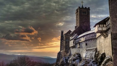 Snowy Wartburg in Eisenach in front of a picturesque and dramatic sky in romantic colors, at dusk,