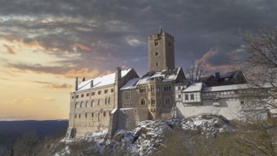 Snowy Wartburg in Eisenach in front of a picturesque and dramatic sky in romantic colors, at dusk,