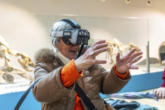 Senior woman wearing a vr headset reaching out with her hands, interacting with a virtual
