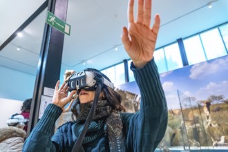 Woman wearing vr goggles, using hand gestures to interact with an immersive digital experience