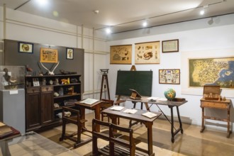 Vintage classroom with old wooden desks, a chalkboard, and display cases showcasing historical