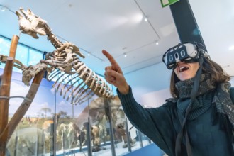 Woman experiencing virtual reality in a natural history museum, interacting with a dinosaur