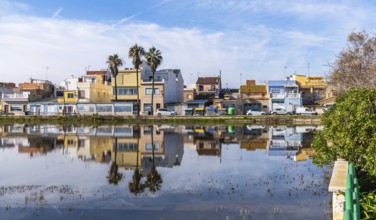 El palmar fishing village houses and palm trees mirrored in the calm albufera lake under a vivid