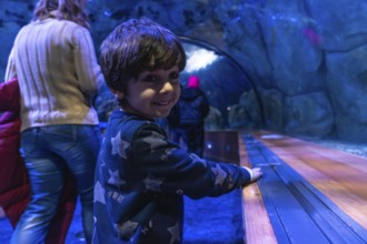 Young child with dark hair smiles, looking over shoulder while enjoying an immersive visit to an