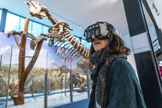 Woman wearing a virtual reality headset exploring an immersive exhibition with an ancient mammal