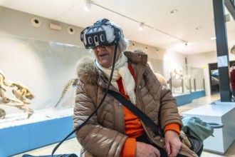 Senior woman wearing a vr headset, experiencing an immersive virtual reality exhibition in a modern