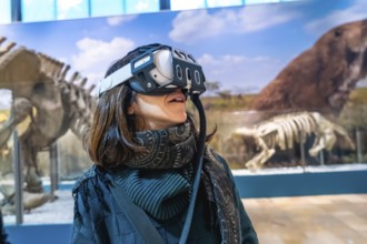 Woman experiencing virtual reality with a headset on, exploring ancient animals and paleontology in