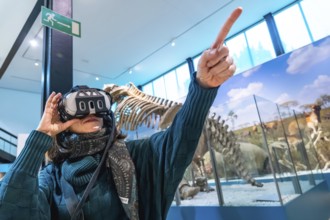 Woman wearing a virtual reality headset and pointing upward, interacting with an immersive