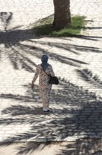 A Tunisian muslim wearing a patterned dress women walks in the streets of Sfax, the second largest